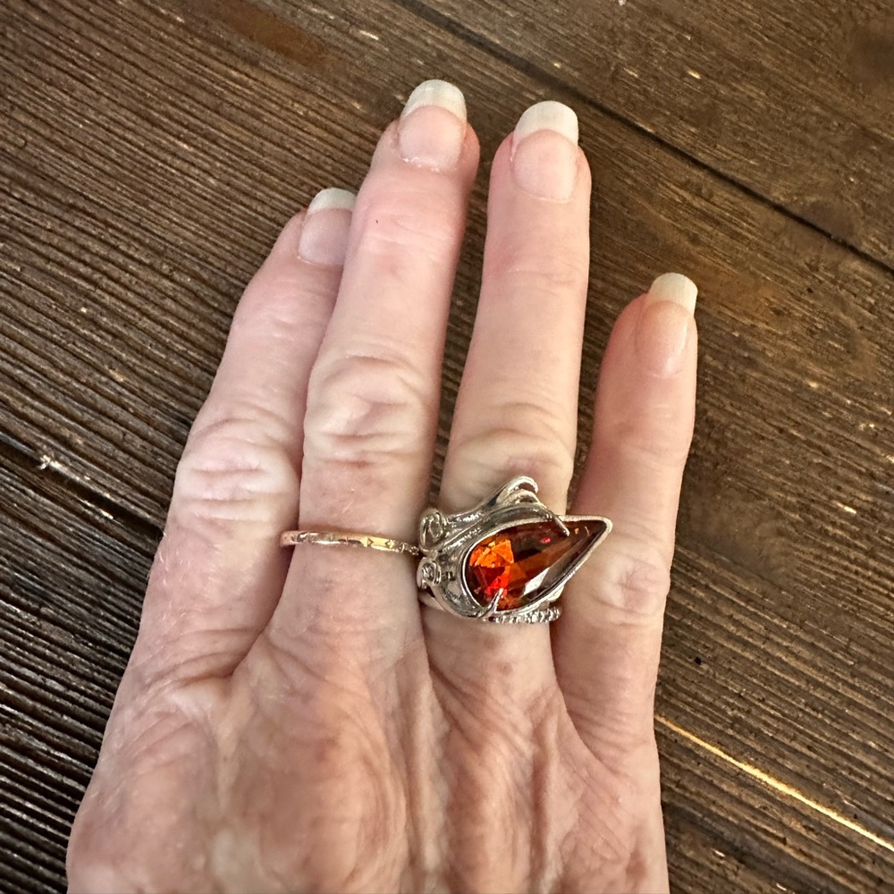 Ring in silver metal intricate with teardrop shaped amber color stone